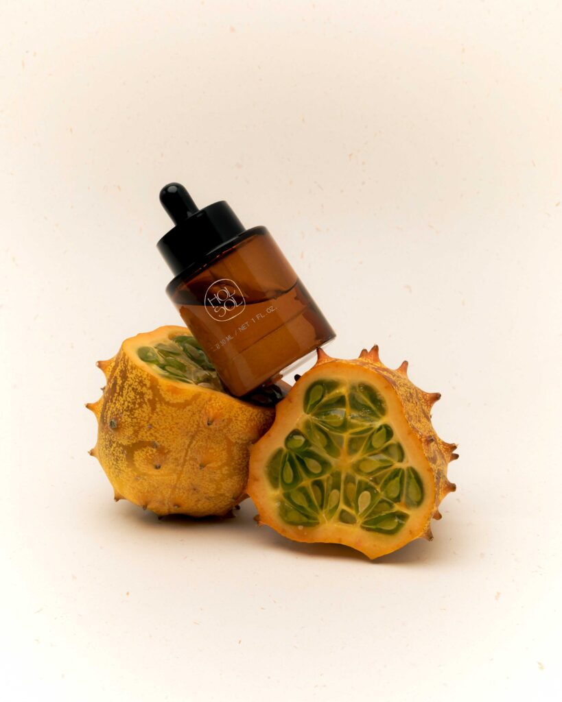 a sliced open dragon fruit with an amber-glass dropper (skincare product) balanced on top